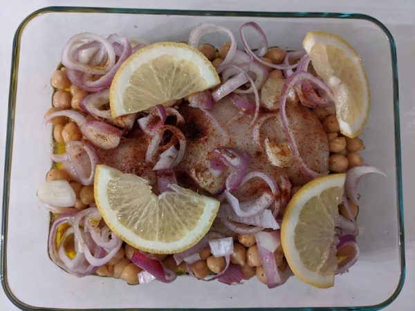 Chicken breast covered in chickpeas, onions, and slices of lemon