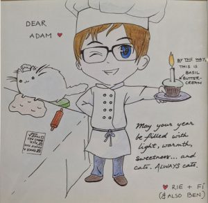 Cartoon drawing of me in a chef outfit holding a cupcake next to a cat kneeding dough.