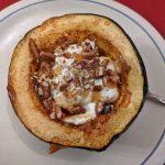 Baked acorn squash topped with greek yoghurt and pecans and drizzled with maple syrup.