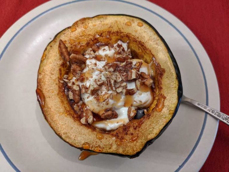 Baked acorn squash topped with greek yoghurt and pecans and drizzled with maple syrup.